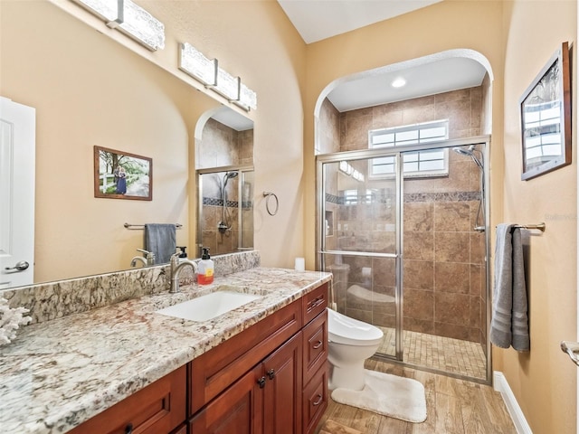 bathroom with hardwood / wood-style flooring, vanity, toilet, and a shower with door