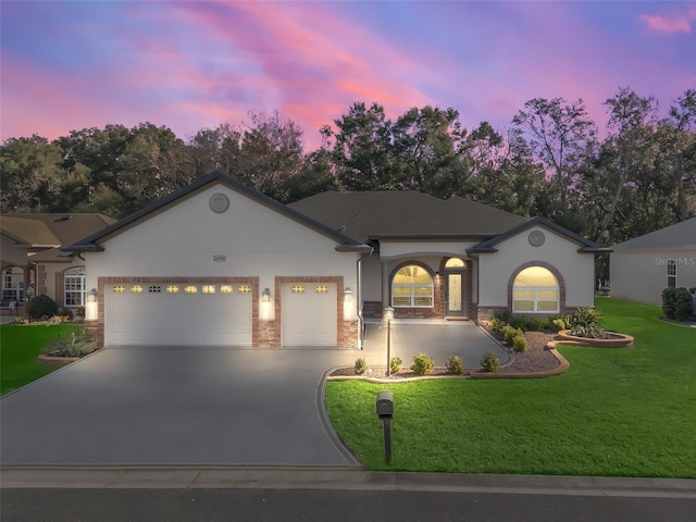 single story home featuring a garage and a lawn