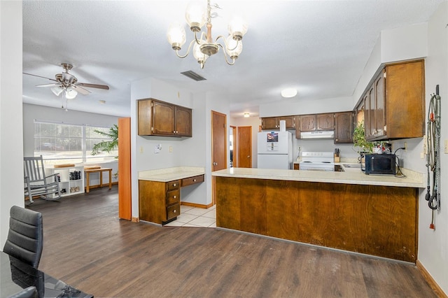 kitchen featuring kitchen peninsula, light wood-type flooring, white appliances, ceiling fan with notable chandelier, and hanging light fixtures