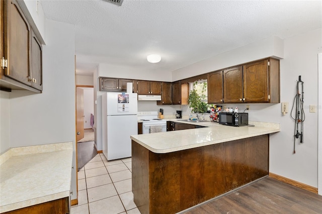 kitchen with sink, light hardwood / wood-style flooring, kitchen peninsula, a textured ceiling, and white appliances