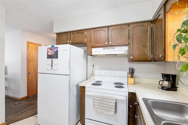 kitchen featuring sink, white appliances, and light wood-type flooring