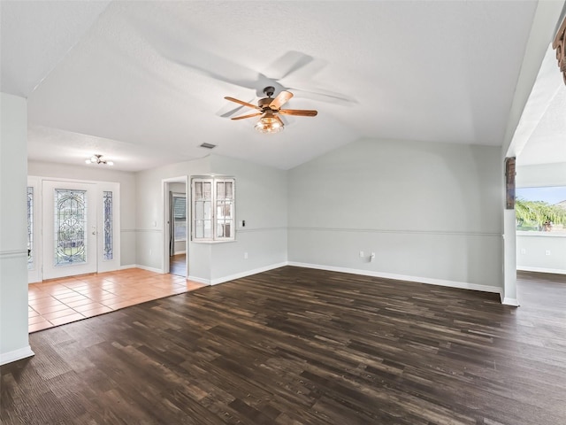 unfurnished living room with dark hardwood / wood-style flooring, vaulted ceiling, a wealth of natural light, and ceiling fan