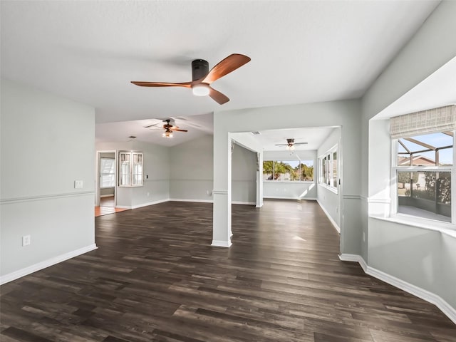 unfurnished living room featuring lofted ceiling, decorative columns, ceiling fan, and dark wood-type flooring