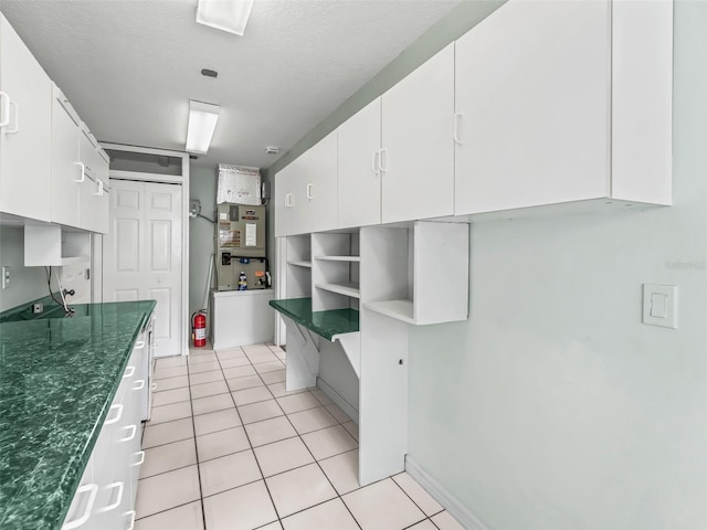 kitchen featuring heating unit, white cabinets, and light tile patterned floors