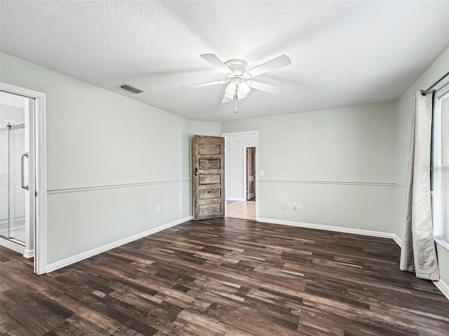 unfurnished room with a textured ceiling, ceiling fan, and dark wood-type flooring