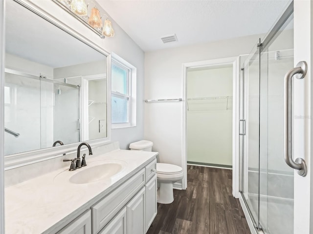 bathroom with hardwood / wood-style flooring, vanity, toilet, and walk in shower