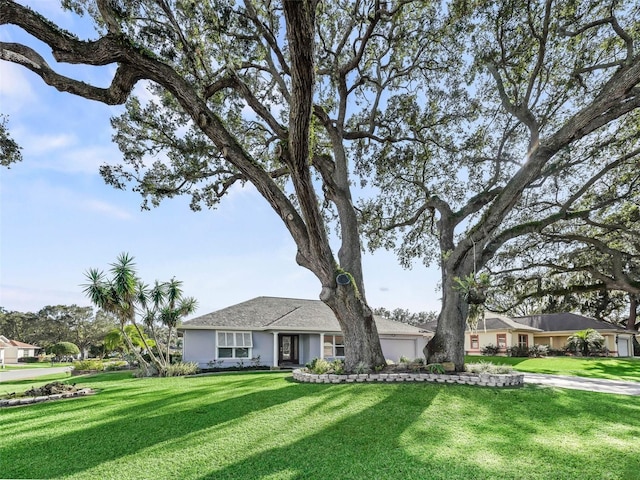 ranch-style house featuring a garage, a front yard, and stucco siding