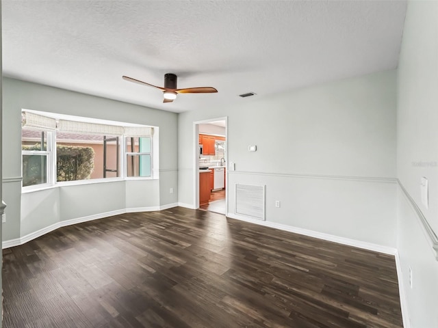 empty room featuring visible vents, dark wood-style flooring, baseboards, and ceiling fan