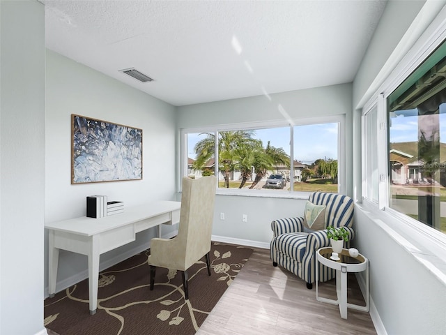 office area featuring a textured ceiling, wood finished floors, baseboards, and visible vents