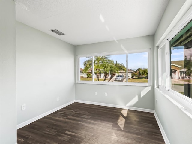 unfurnished room with visible vents, baseboards, a textured ceiling, and wood finished floors