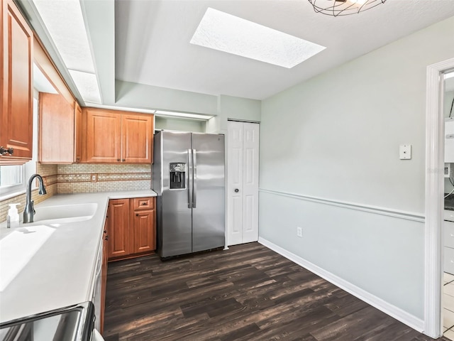 kitchen with a sink, stainless steel fridge, dark wood finished floors, a skylight, and range