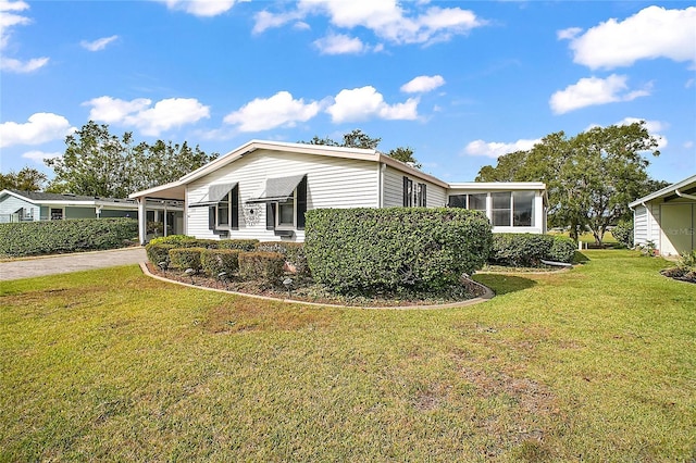 view of property exterior featuring a sunroom, a yard, and a carport