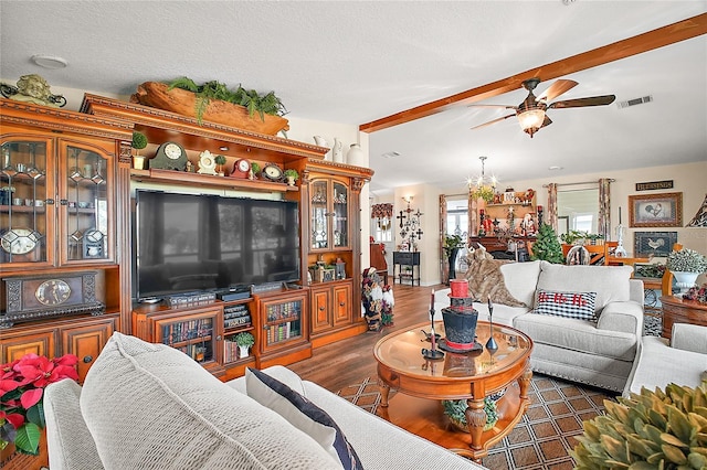 living room with ceiling fan with notable chandelier, dark wood-type flooring, and a textured ceiling