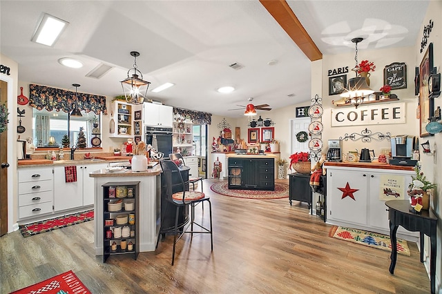 kitchen with ceiling fan, decorative light fixtures, white cabinetry, light hardwood / wood-style floors, and oven