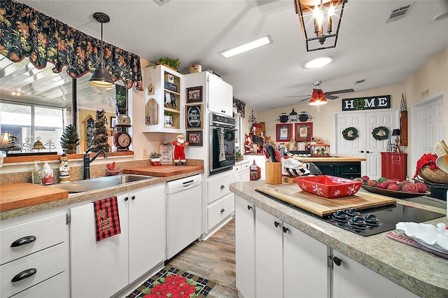 kitchen with dishwasher, sink, vaulted ceiling, decorative light fixtures, and white cabinets