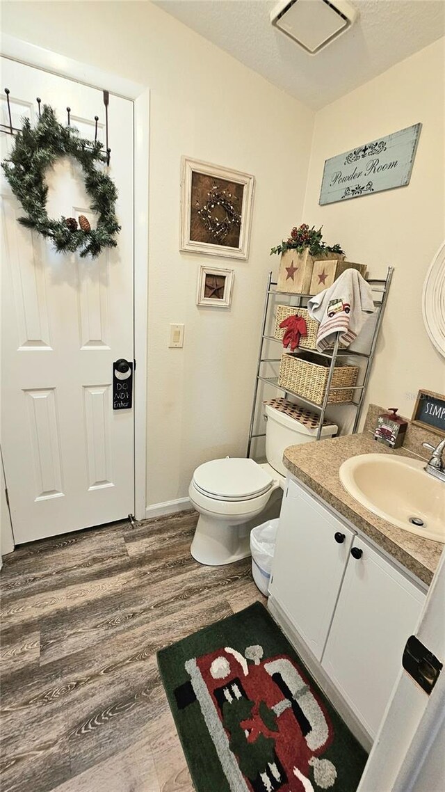 bathroom featuring vanity, toilet, wood-type flooring, and a textured ceiling