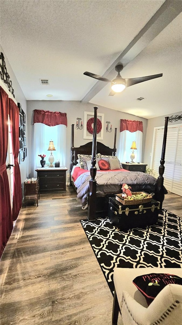 bedroom with wood-type flooring, a textured ceiling, ceiling fan, and beam ceiling