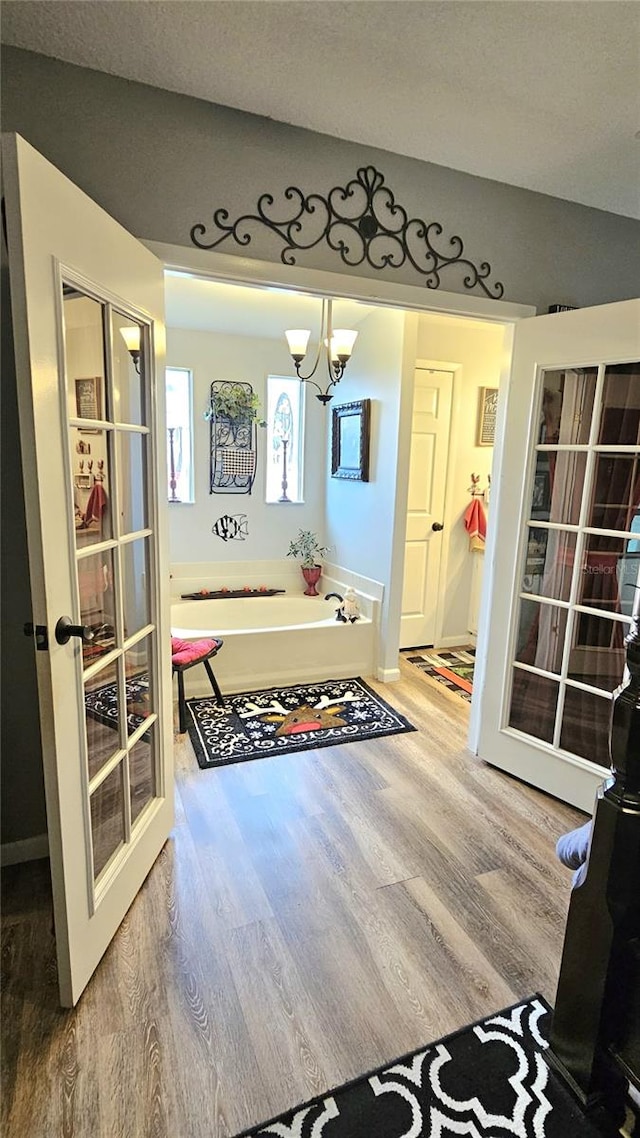 bathroom with french doors, wood-type flooring, and a notable chandelier