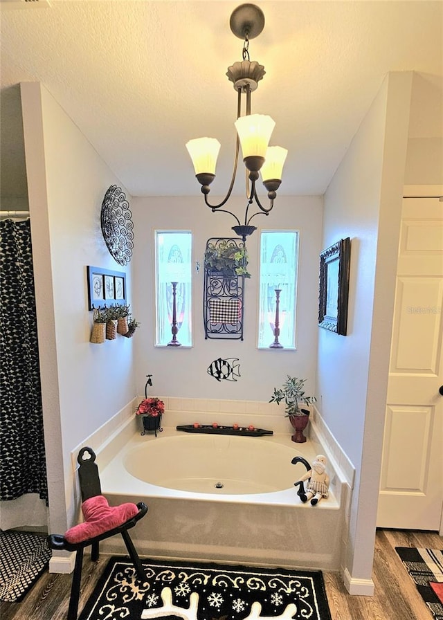 bathroom featuring a bath, wood-type flooring, a textured ceiling, and an inviting chandelier