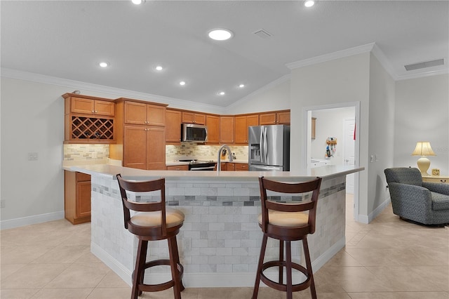 kitchen with a kitchen breakfast bar, backsplash, stainless steel appliances, and vaulted ceiling