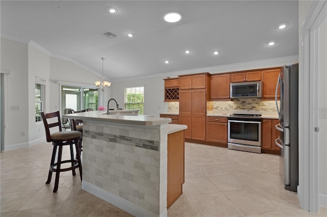 kitchen featuring stainless steel appliances, hanging light fixtures, ornamental molding, and a breakfast bar area