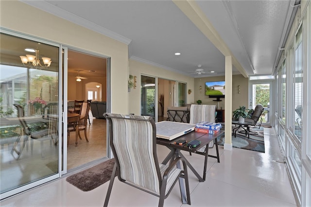 sunroom featuring ceiling fan with notable chandelier