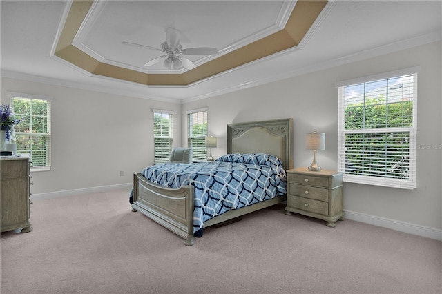 carpeted bedroom with a tray ceiling, ceiling fan, and ornamental molding