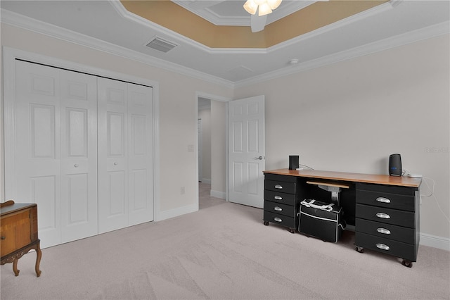 carpeted home office with a tray ceiling, crown molding, and ceiling fan