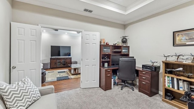 office space featuring light carpet, a tray ceiling, and ornamental molding