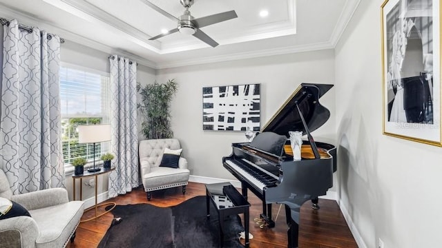 living area with ornamental molding, dark hardwood / wood-style floors, a tray ceiling, and a healthy amount of sunlight