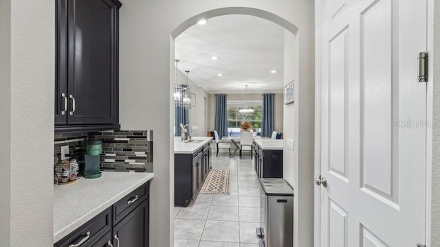 kitchen featuring light stone countertops, sink, decorative light fixtures, decorative backsplash, and light tile patterned floors