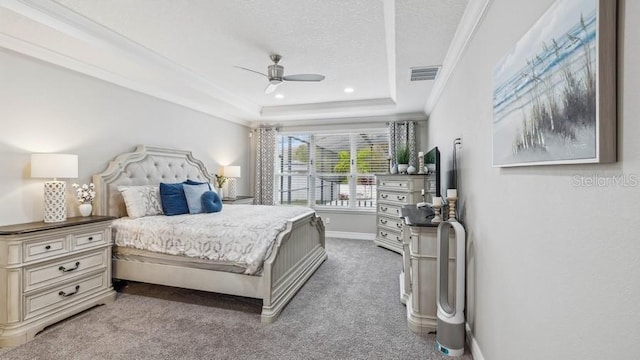 bedroom with ceiling fan, carpet floors, a textured ceiling, a tray ceiling, and ornamental molding