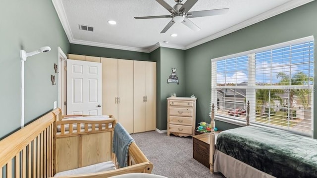 carpeted bedroom featuring a textured ceiling, ceiling fan, and ornamental molding