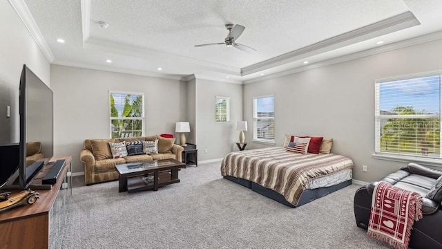 carpeted bedroom with ceiling fan, a raised ceiling, a textured ceiling, and crown molding