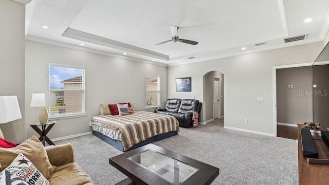 carpeted bedroom with a raised ceiling, ceiling fan, a textured ceiling, and ornamental molding