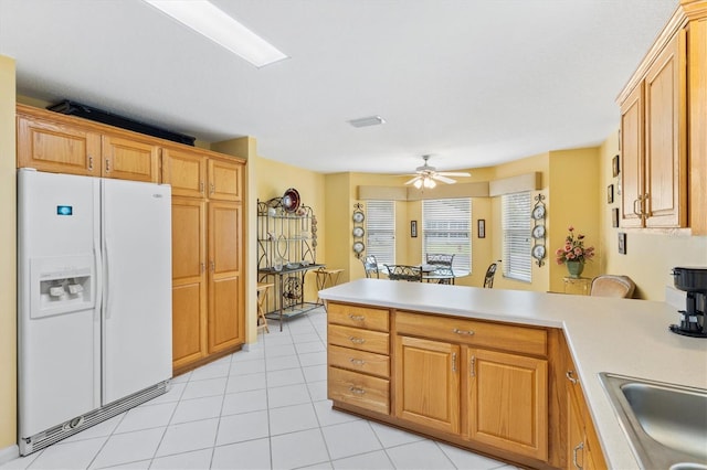 kitchen with white refrigerator with ice dispenser, sink, ceiling fan, light tile patterned flooring, and kitchen peninsula