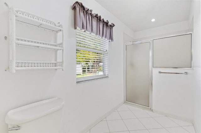 bathroom featuring tile patterned flooring, toilet, and a shower with shower door