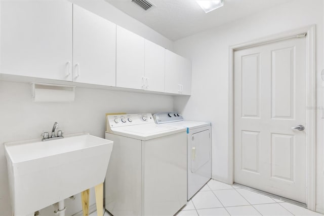 laundry room featuring washer and clothes dryer, cabinets, sink, light tile patterned floors, and a textured ceiling