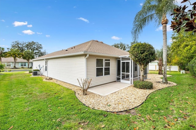 back of property featuring a sunroom, a patio area, and a lawn