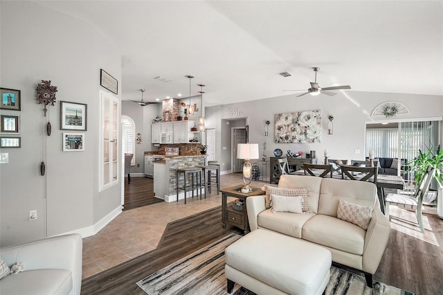 living room with ceiling fan, wood-type flooring, and lofted ceiling