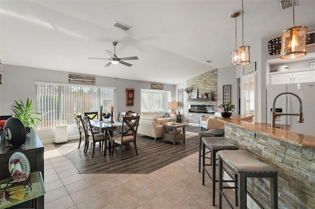 dining area with ceiling fan, sink, light hardwood / wood-style floors, vaulted ceiling, and a fireplace