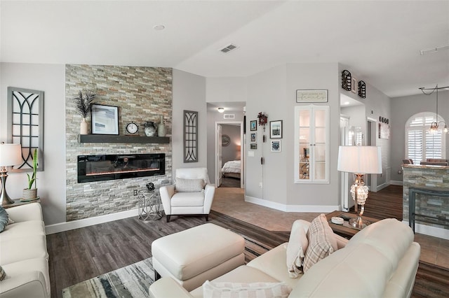 living room with dark hardwood / wood-style flooring, a stone fireplace, and lofted ceiling