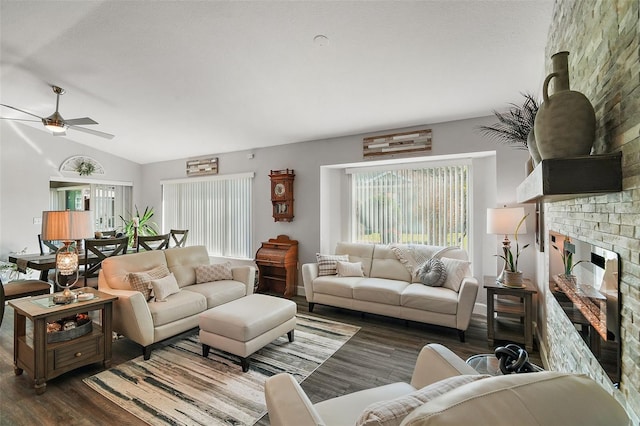 living room featuring ceiling fan, lofted ceiling, dark wood-type flooring, and a brick fireplace