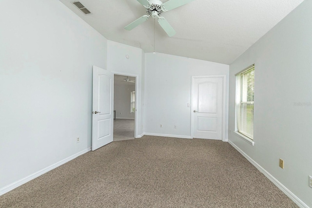 carpeted empty room with ceiling fan, lofted ceiling, and a textured ceiling