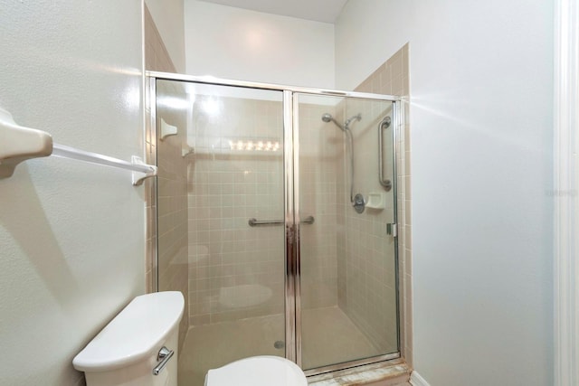 bathroom with toilet and a shower with shower door