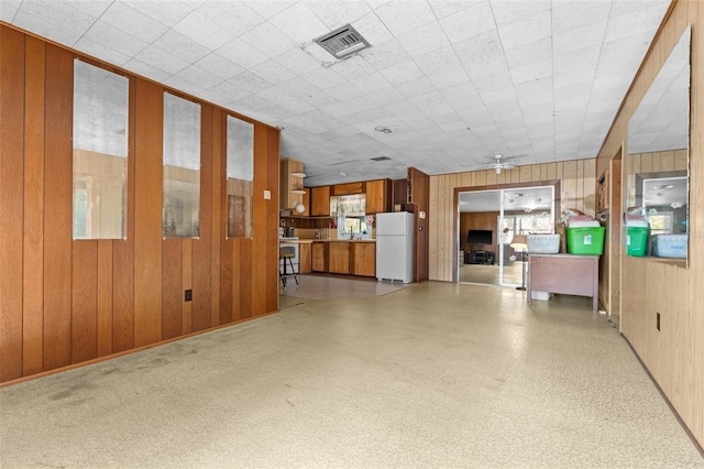 interior space featuring ceiling fan and wood walls