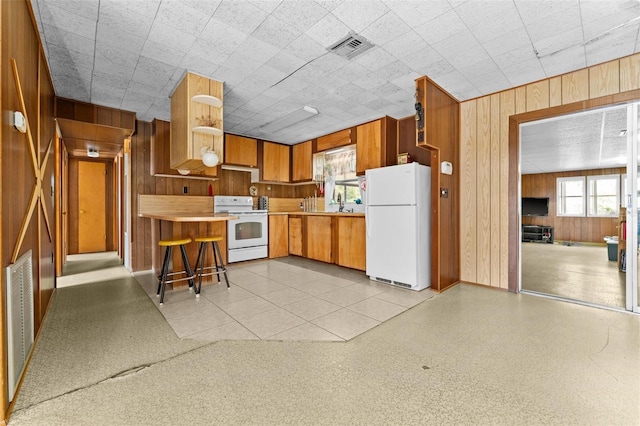 kitchen with wood walls, white appliances, and sink