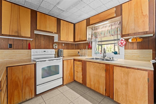 kitchen with wood walls, sink, light tile patterned flooring, and white electric range oven