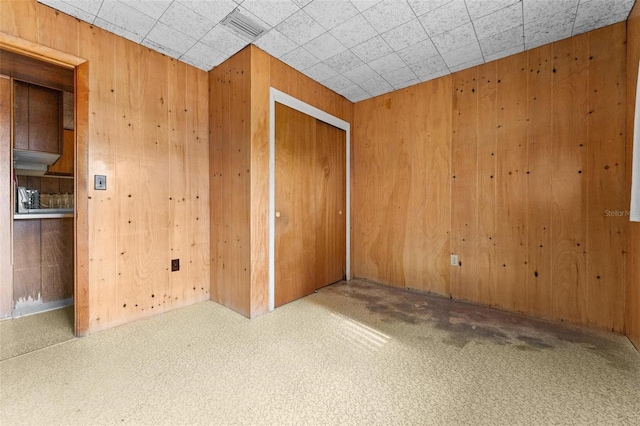 unfurnished room with carpet and wood walls