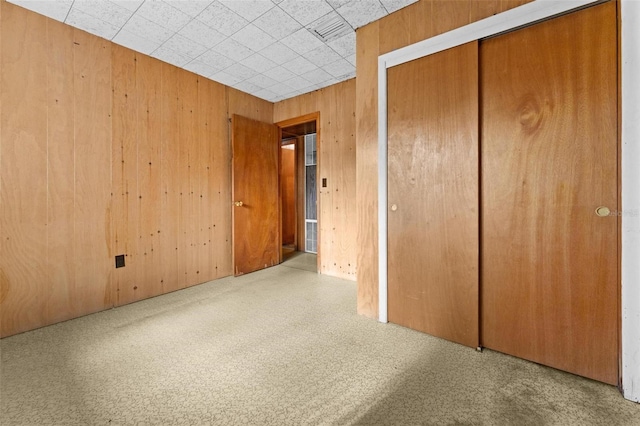 unfurnished bedroom with wood walls and a closet